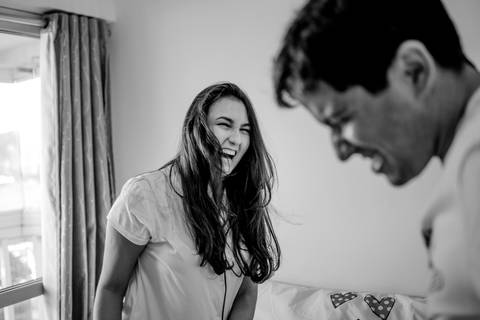 Esposa rindo do esposo. Fotografia de casal. Ensaio realizado em casa.'