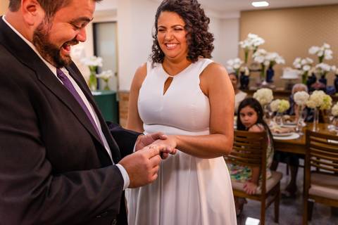 Noivo colocando aliança no dedo da noiva'