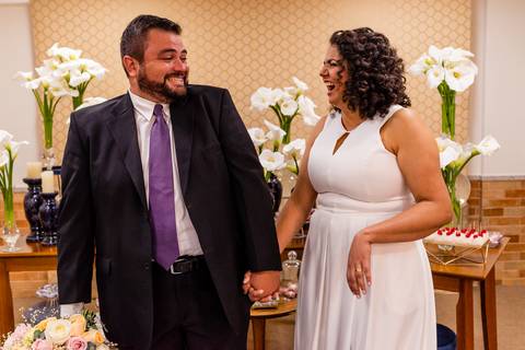 Noivos gargalhando ao posar para fotografia'