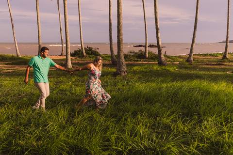 Casal caminhando sobre o gramado entre os coqueiros na praia de coqueiral de aracruz no espírito santo.'