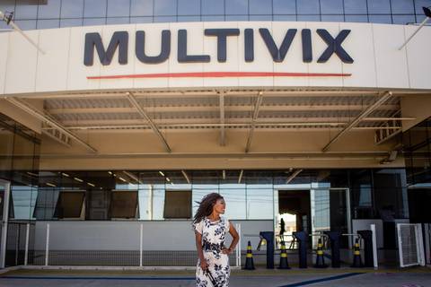 Formanda posando para foto na fachada da faculdade multivix.'