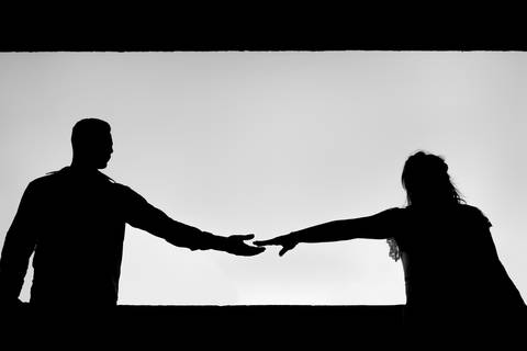 Fotografia preto e branco em silhueta do casal dando as maos.'
