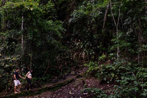 Ensaio Fotográfico realizado na cachoeira do Aloísio em Viana, Espírito Santo. Casal da foto está subindo uma estrada de pedras e ao fundo rochas cheias de arvores compondo a vegetação.'