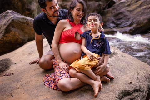 Familia sentada na pedra da cachoeira em ensaio fotografico de gestante realizado na cachoeira em viana.'