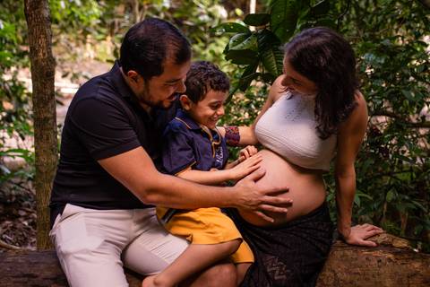 Fotografia da familia olhando para barriga da mãe gravida.'