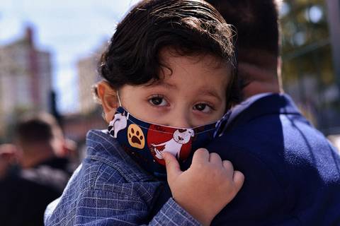 filho no colo do pai, de mascara'