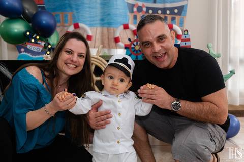 Foto dos pais com o aniversariante da frente do bolo'