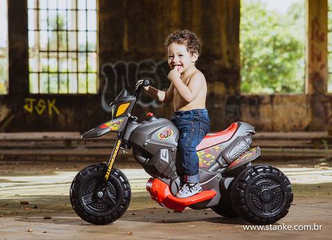 Arthur montado em sua motoca, com a mão na boca,  no seu ensaio de 01 ano, realizado na Rotunda, em  Campo Grande-MS. Fotos feitas por Pedro Stanke,'