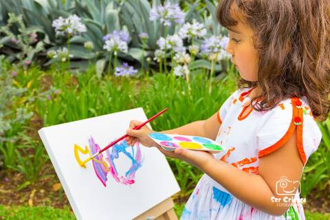 Menina pintando quadro durante ensaio infantil'