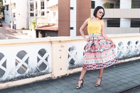 modelo de pé segura sua saia e faz pose para fotografo'