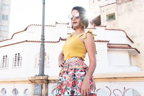 modelo faz pose de pé usando oculos escuros raio de sol saindo da cabeça'