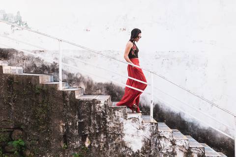 modelo com saia vermelha desce as escadas'