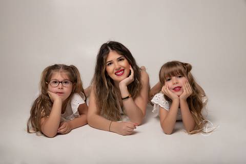 foto de mae e filhas com a mao no queixo'