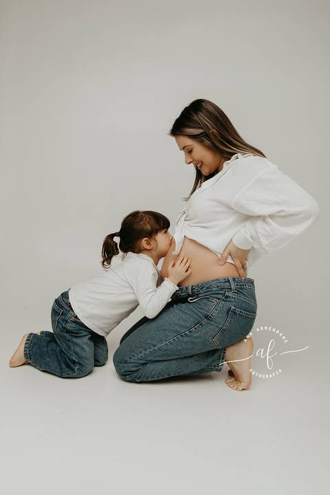 Foto grávida com a filha beijando a barriga'