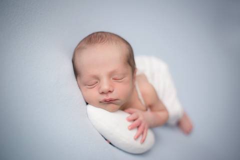 Newborn pose lateral em manta azul, ensaio Brasilia DF'