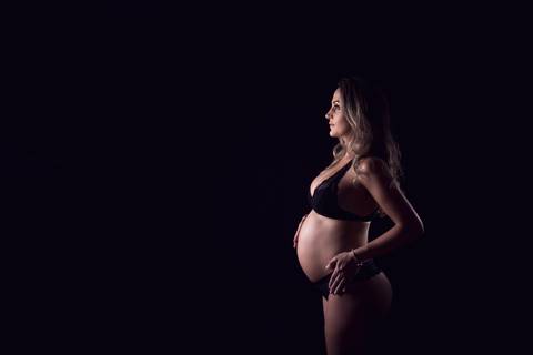 Foto atemporal de gestante em estúdio de Brasilia, fundo preto '