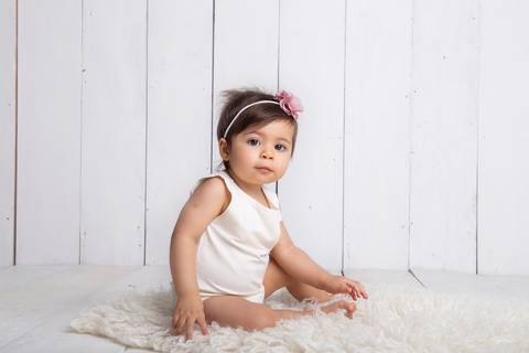 Bebê sentada em cenário branco, para seu ensaio de 9 meses, acompanhamento trimestral Brasilia DF'