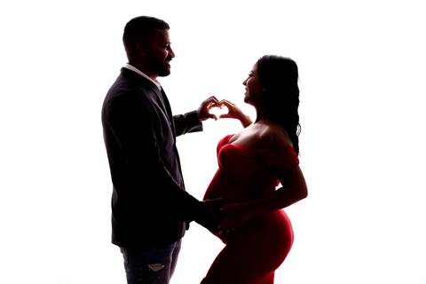 O fundo neutro e a iluminação suave destacam a silhueta da gestante, transmitindo uma sensação de paz e serenidade.'