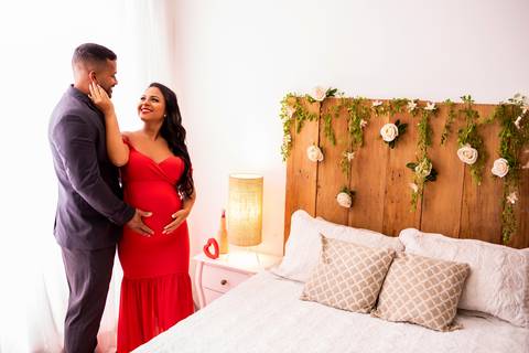 A gestante, envolta em um tecido translúcido, irradia um brilho especial enquanto aguarda a chegada do seu bebê.'