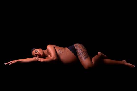 A imagem retrata a gestante em um momento de contemplação, com uma expressão tranquila e serena, revelando a conexão profunda com seu bebê.'