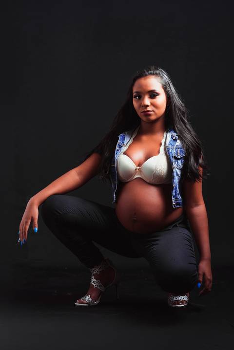 Uma imagem impactante de Julia, no fundo preto, captura sua feminilidade e sensualidade, revelando a beleza única e natural da maternidade.'