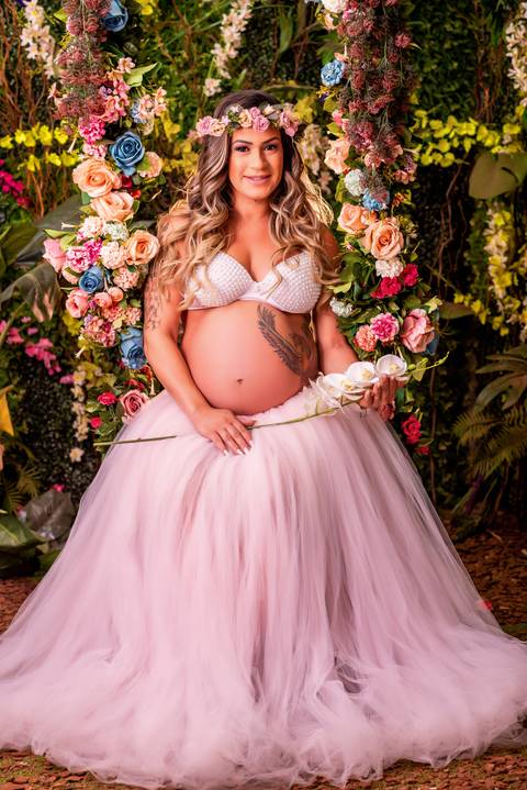 Nesta foto, a futura mamãe brilha no cenário clean, com uma delicada luz suave realçando sua beleza natural.'