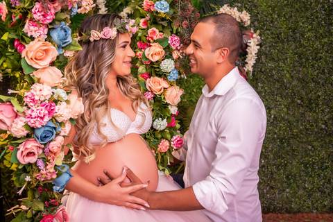 A gestante brilha no cenário do Jardim Encantado, com sua barriga protuberante e um sorriso radiante que ilumina a fotografia.'