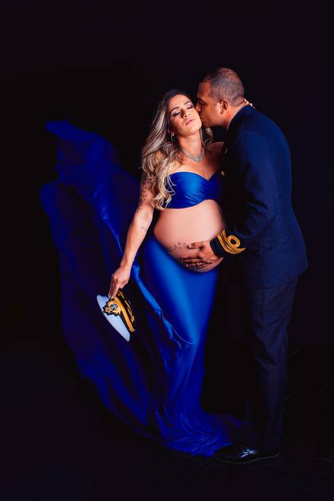 Uma foto com tecido esvoaçante ao vento retrata a gestante em um momento de conexão com a natureza e com seu bebê.'