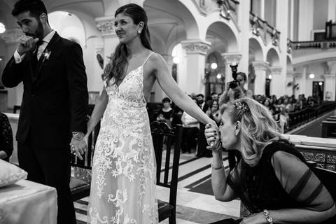 Madre de la novia besa la mano en el altar.'