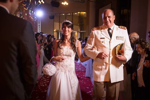 Entrada de la novia con su padrino vistiendo uniforme militar. Novio espera en el altar momentos antes  de la ceremonia el día de su boda en Federación, Entre Ríos. Fotografo de bodas Erika Fayolle en Rosario, Buenos Aires.'