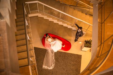 Novios, retrato en el sillón rojo y las escaleras del hotel Arena de Federación. Fotografo de bodas Erika Fayolle en Rosario, Buenos Aires.'