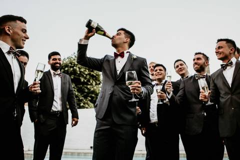 Novio brindis con amigos en los preparativos de la boda. Fotografía Campos de Ibarlucea.'