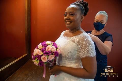 mãe fechando o vestido da noiva'