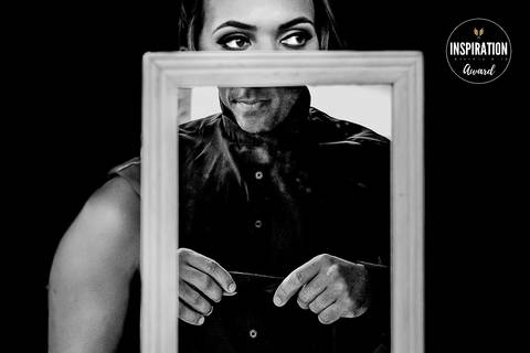 Imagem em preto e branco premiada que mostra o noivo em preparação, ajustando sua gravata. A composição única com o uso do espelho destaca seus olhos expressivos, criando uma atmosfera de expectativa e emoção.'