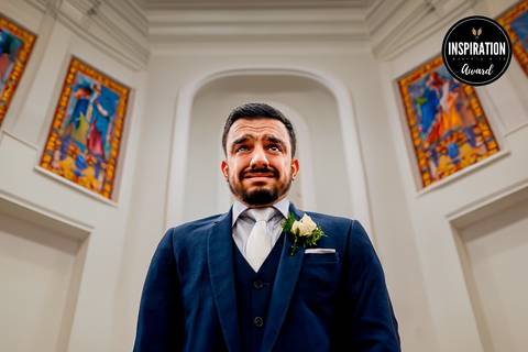 Momento emocionante do noivo à espera da noiva no altar, em uma cerimônia repleta de sentimentos intensos. Sua expressão traduz a ansiedade e o amor vivenciados nesse instante único, que ficará eternizado nas memórias do casamento.'