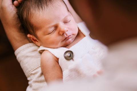 pai carregando bebe recém nascido'