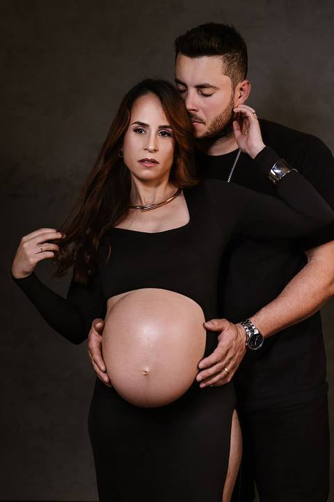 Detalhe da barriga da gestante com as mãos do casal, simbolizando afeto e conexão durante a espera pelo Samuel.'