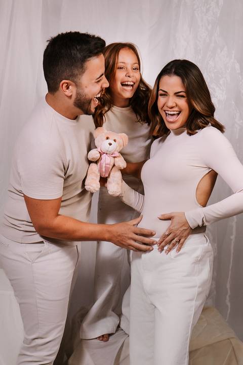 Fotografia descontraída dos pais celebrando a chegada da Luna com o presente temático.'