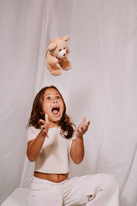 Retrato divertido da Malu comemorando a chegada da irmã durante o ensaio.'