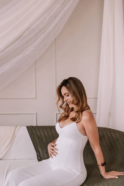 Gestante sorrindo enquanto segura a filha pequena'