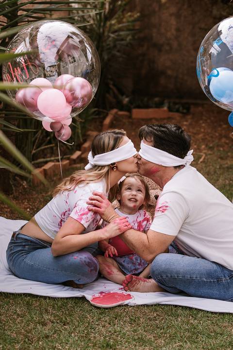Pai e mãe beijando a filha vendada durante a brincadeira'