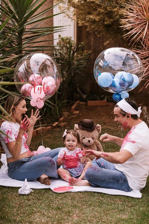 Família comemorando com balões rosa após descobrir que é menina'