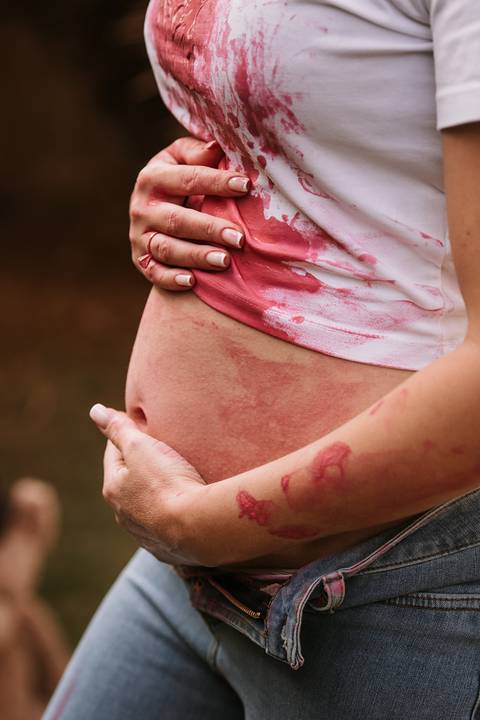 Close da barriga com tinta rosa da revelação'
