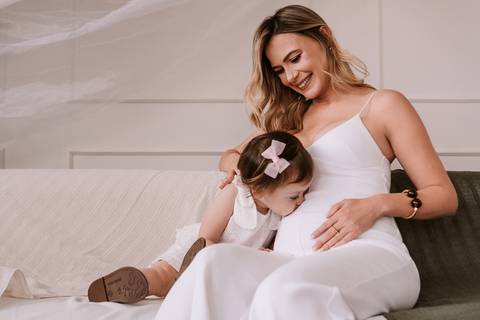 Mãe e filha sentadas na cama brincando juntas'