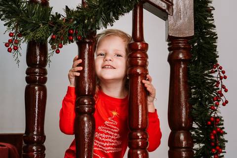 Criança sorrindo ao lado da guirlanda de Natal'