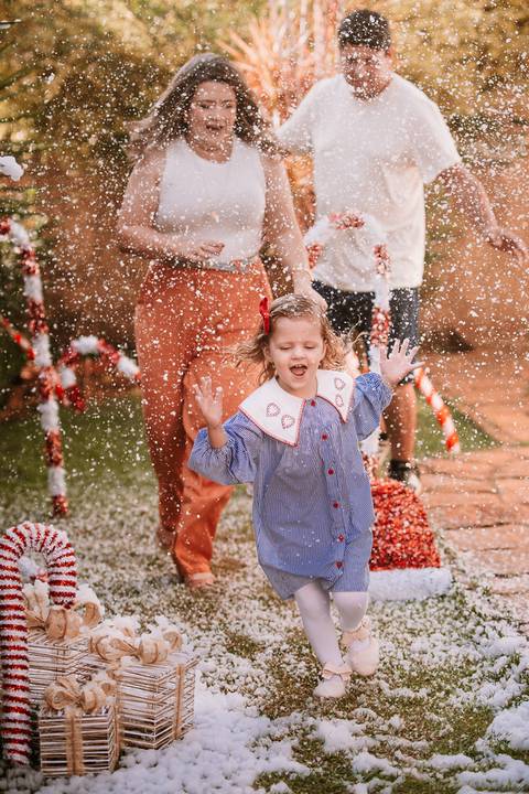 Criança sorrindo enquanto brinca no cenário externo de Natal'