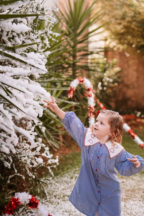 Criança sorrindo enquanto observa neve no cenário externo'