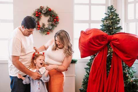 Pai levantando a filha enquanto a mãe observa sorrindo'