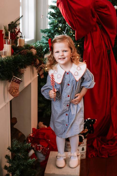 Larinha sorrindo segurando um pirulito natalino'