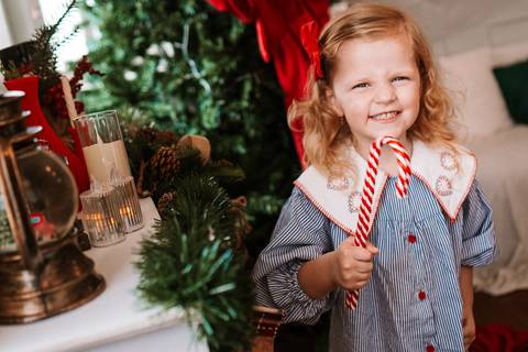 Larinha sorrindo segurando um pirulito natalino'